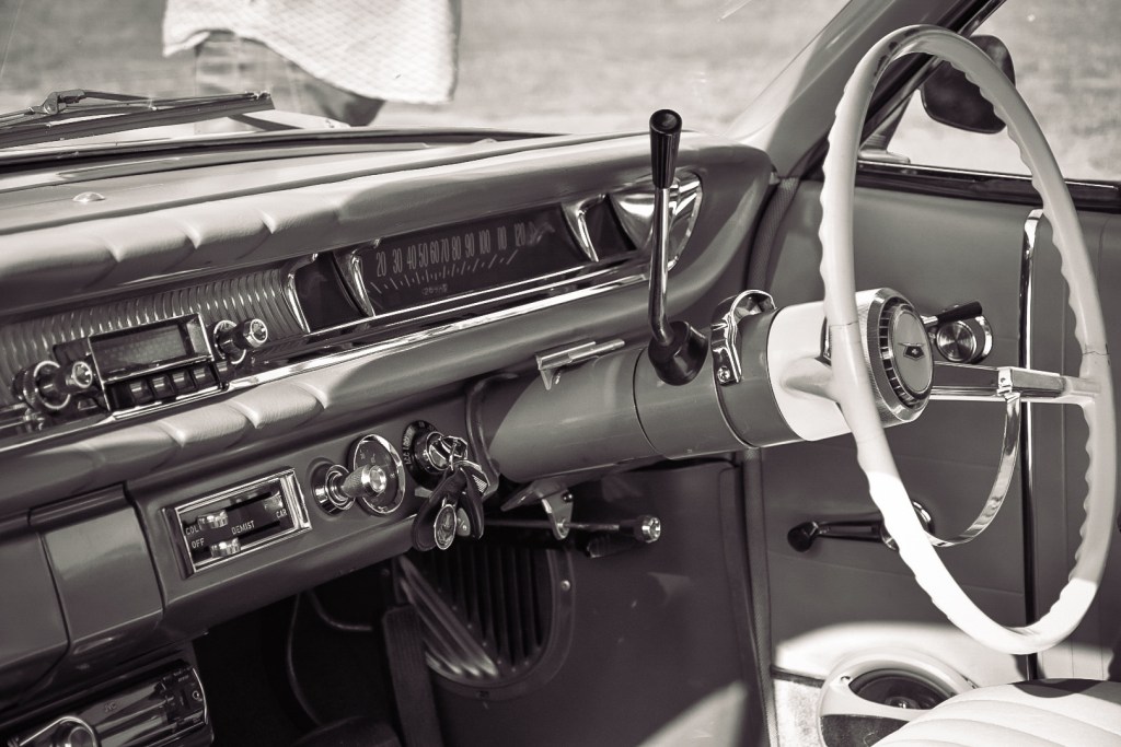 Interior view of a vintage 1964 Chevrolet Bel Air dashboard featuring a classic chrome radio, steering wheel, and various controls.